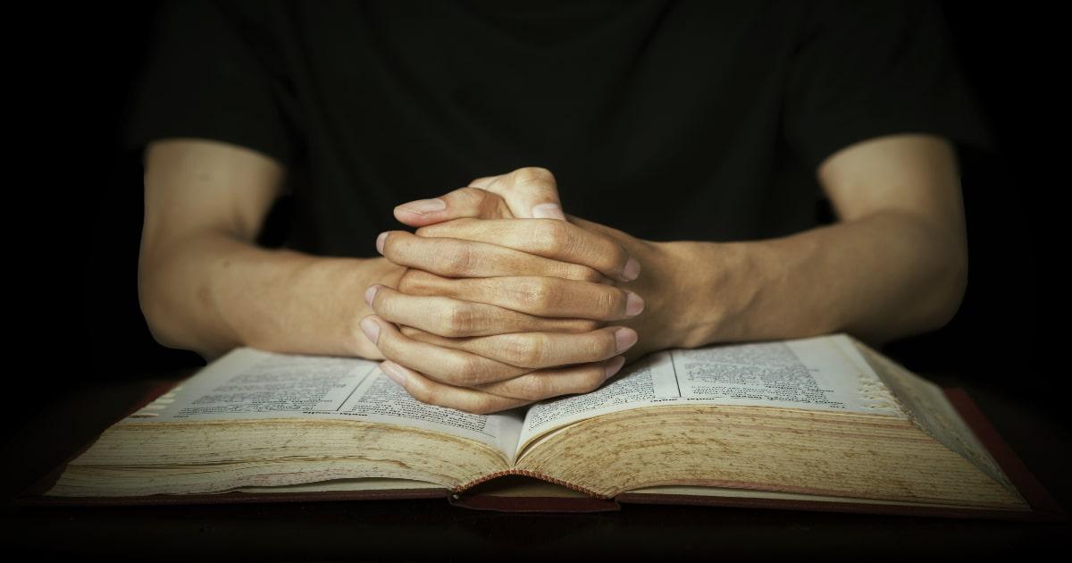 hands on a bible praying