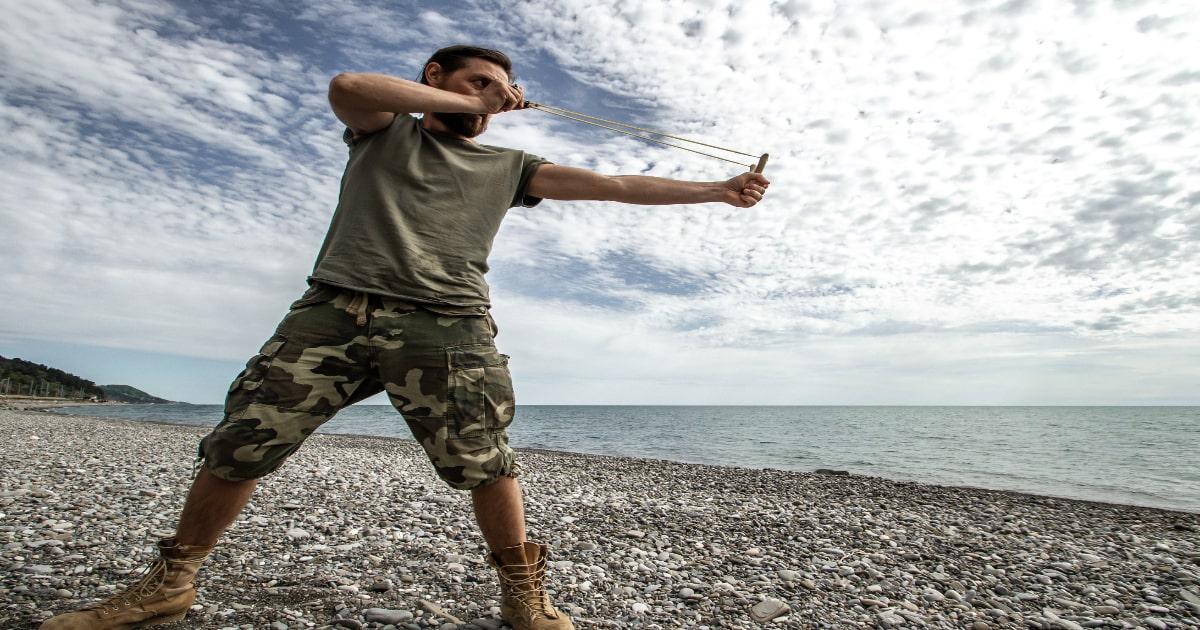 prepper with slingshot on beach