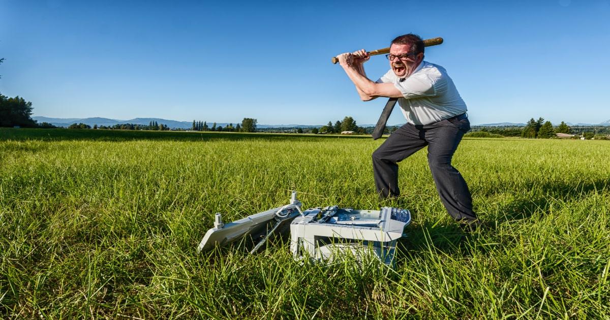 man smashing up a computer in a field